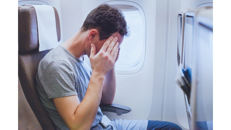 headache in the airplane, man passenger afraid and feeling bad during flight, fear