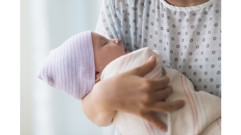 Asian mother holding newborn baby in hospital