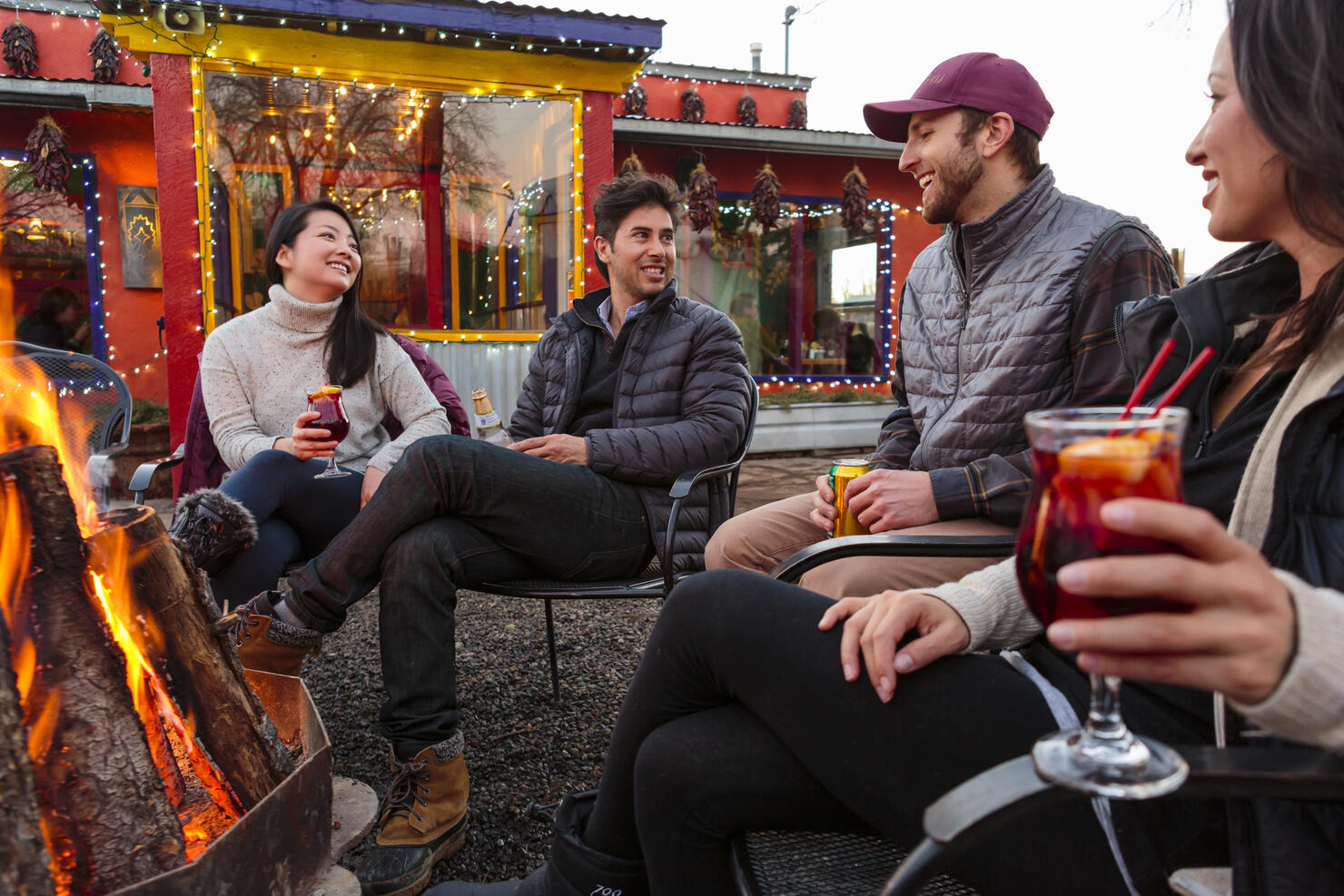 Couples drinking cocktails and beer outdoors at storefront campfire