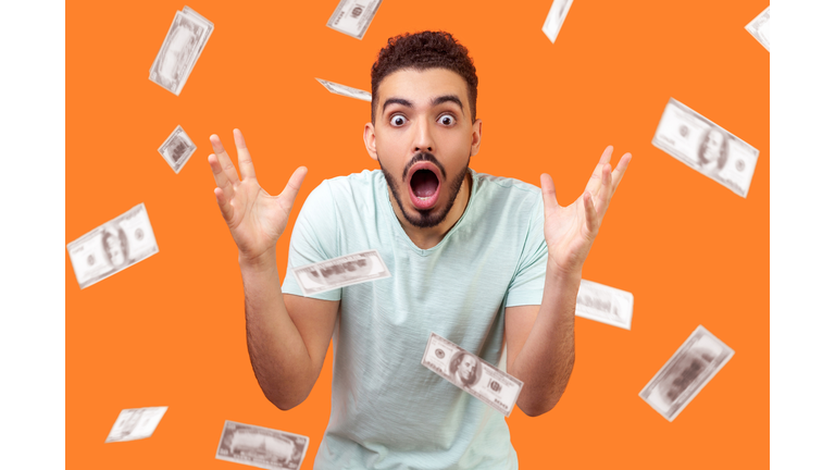 Oh my god, wow! Portrait of amazed man looking at camera with big eyes and open mouth, absolutely shocked of money rain falling from up.