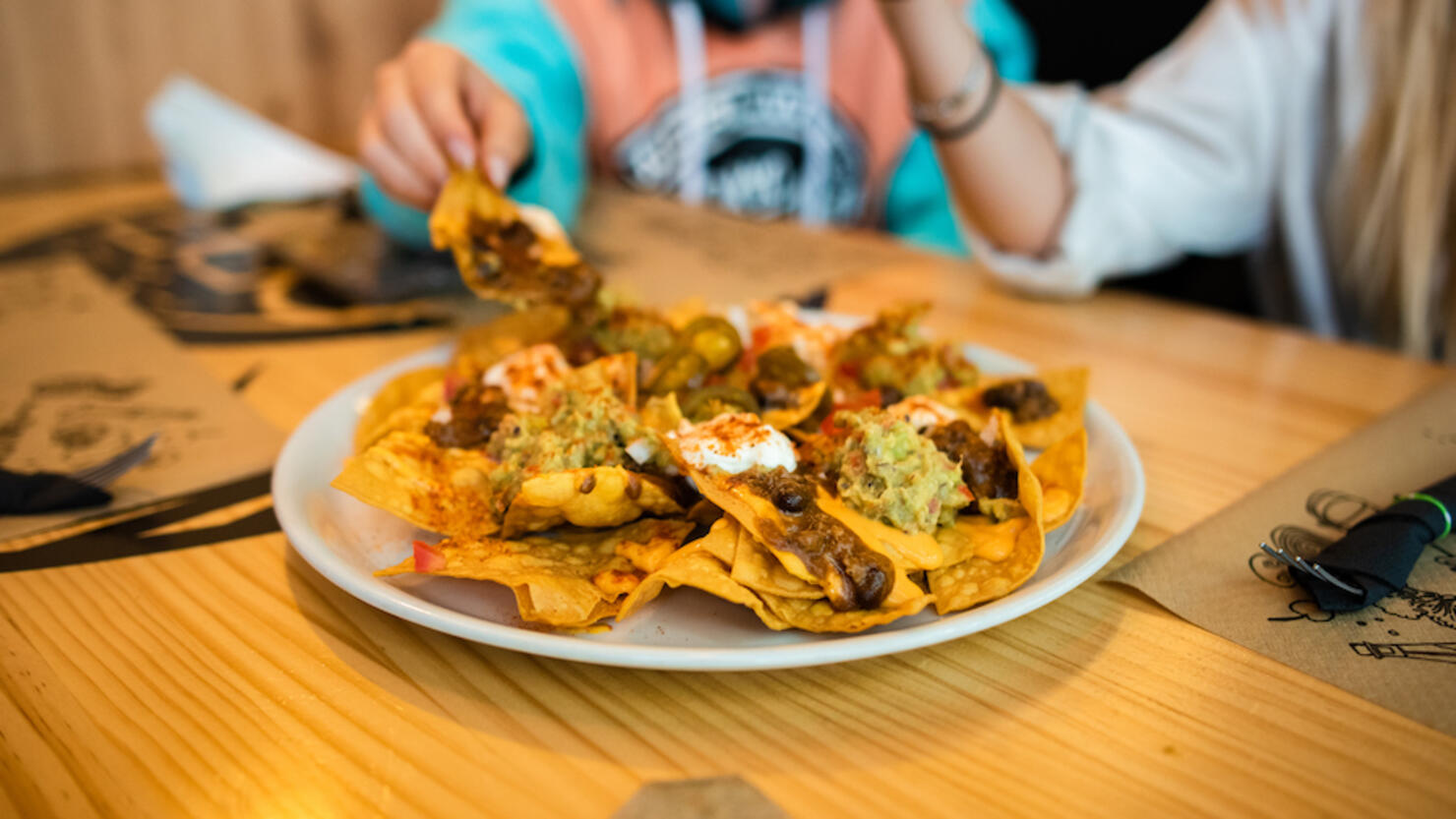 Young women eating nachos inside a restaurant