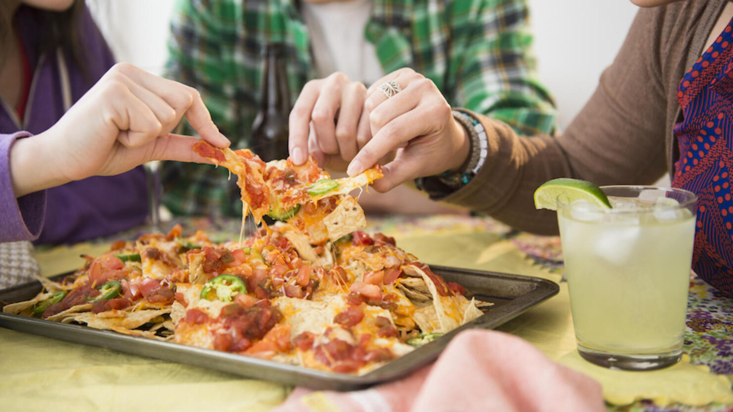 Young women and man eating nachos with melted cheese