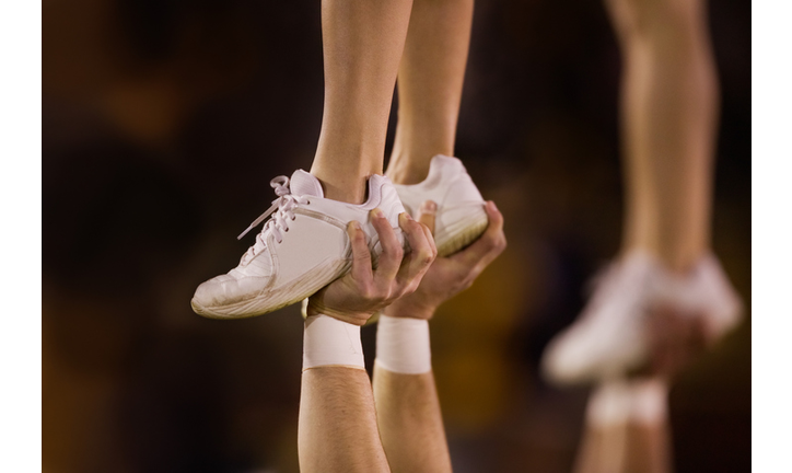 Male cheerleader lifting female cheeleader above his head, close-up