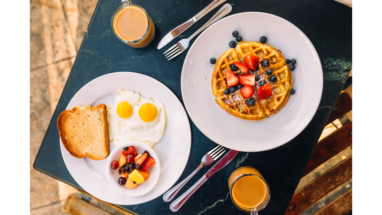 Breakfast with sunny side up fried eggs, waffle and fruits