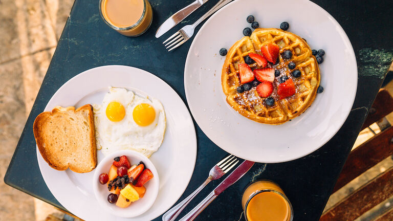 Breakfast with sunny side up fried eggs, waffle and fruits