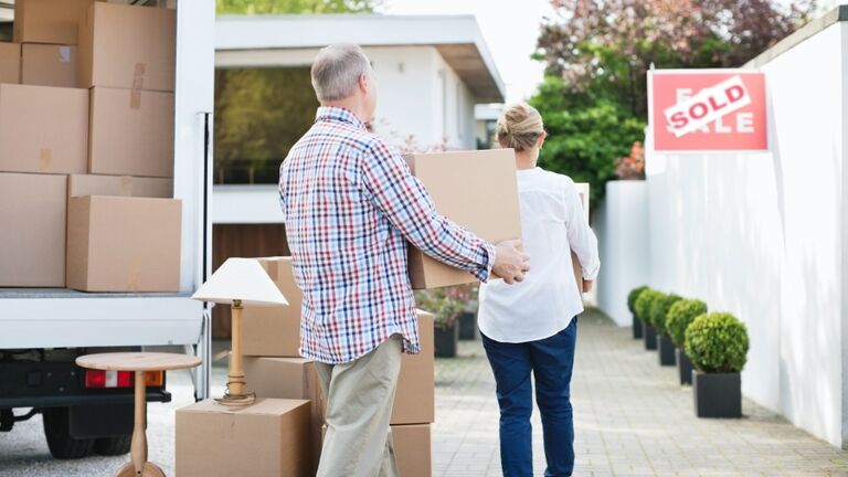 Couple unloading boxes from moving van