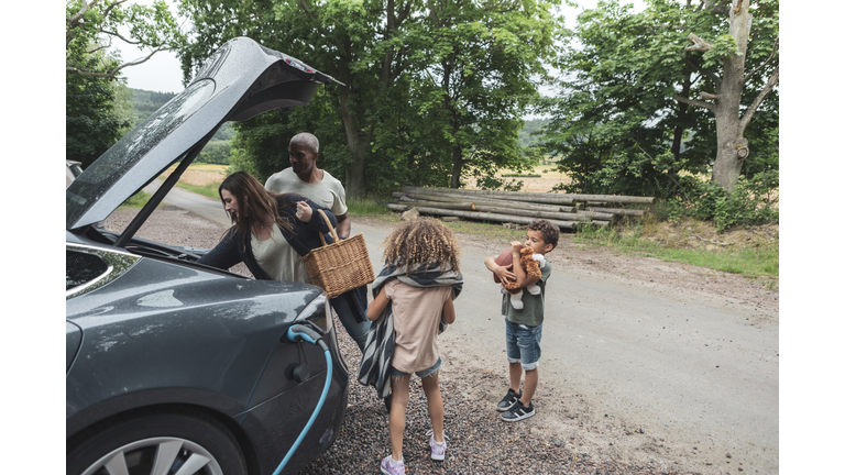 Woman unloading luggage with family during picnic