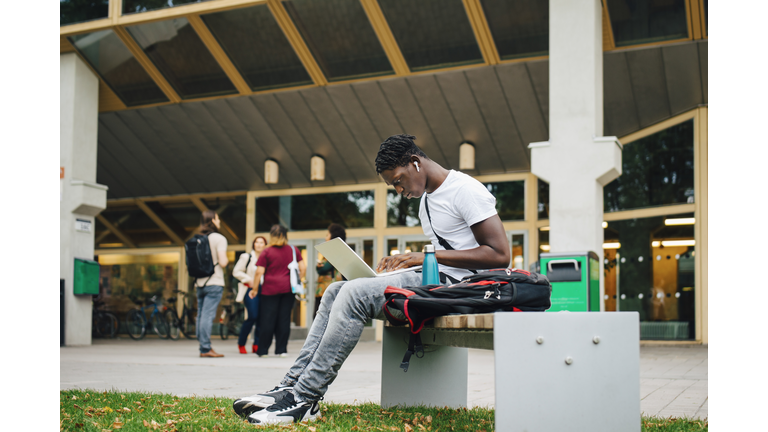 Male college student e-learning on laptop in campus
