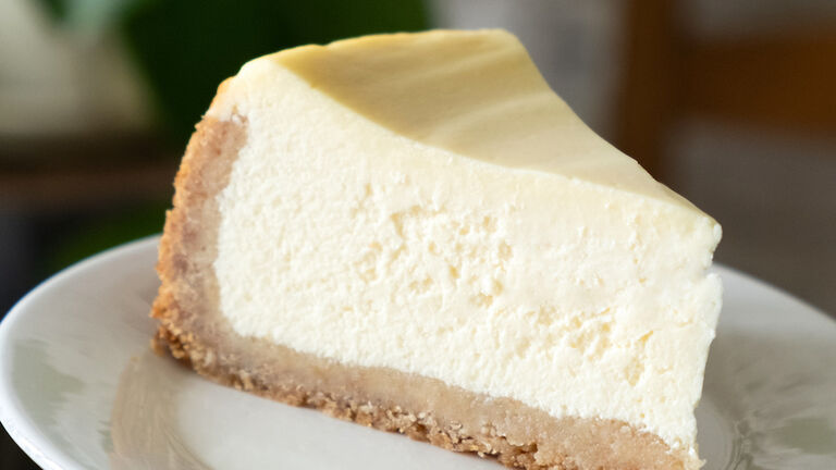 Slice of cheesecak on plate in hands