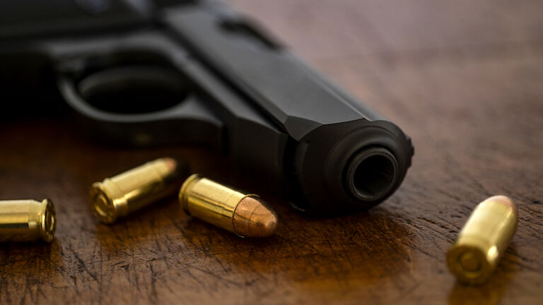 Gold bullets and pistol on wooden surface