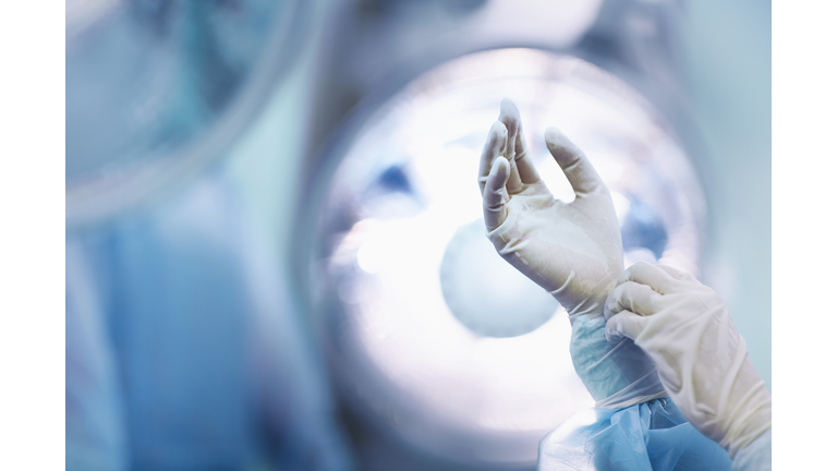 Surgeon adjusting glove in operating room