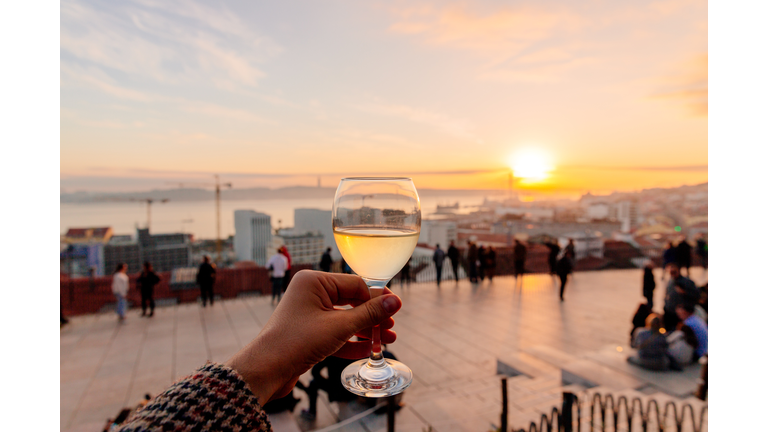 Drinking vinho verde (green wine) with view of Lisbon skyline at Miradouro de Santa Catarina, Portugal