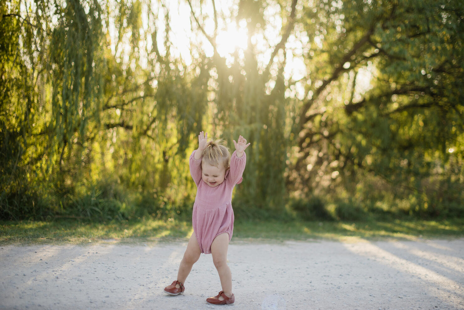 baby girl playing on dirt road at sunset