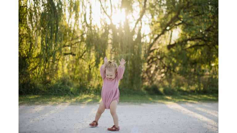 baby girl playing on dirt road at sunset