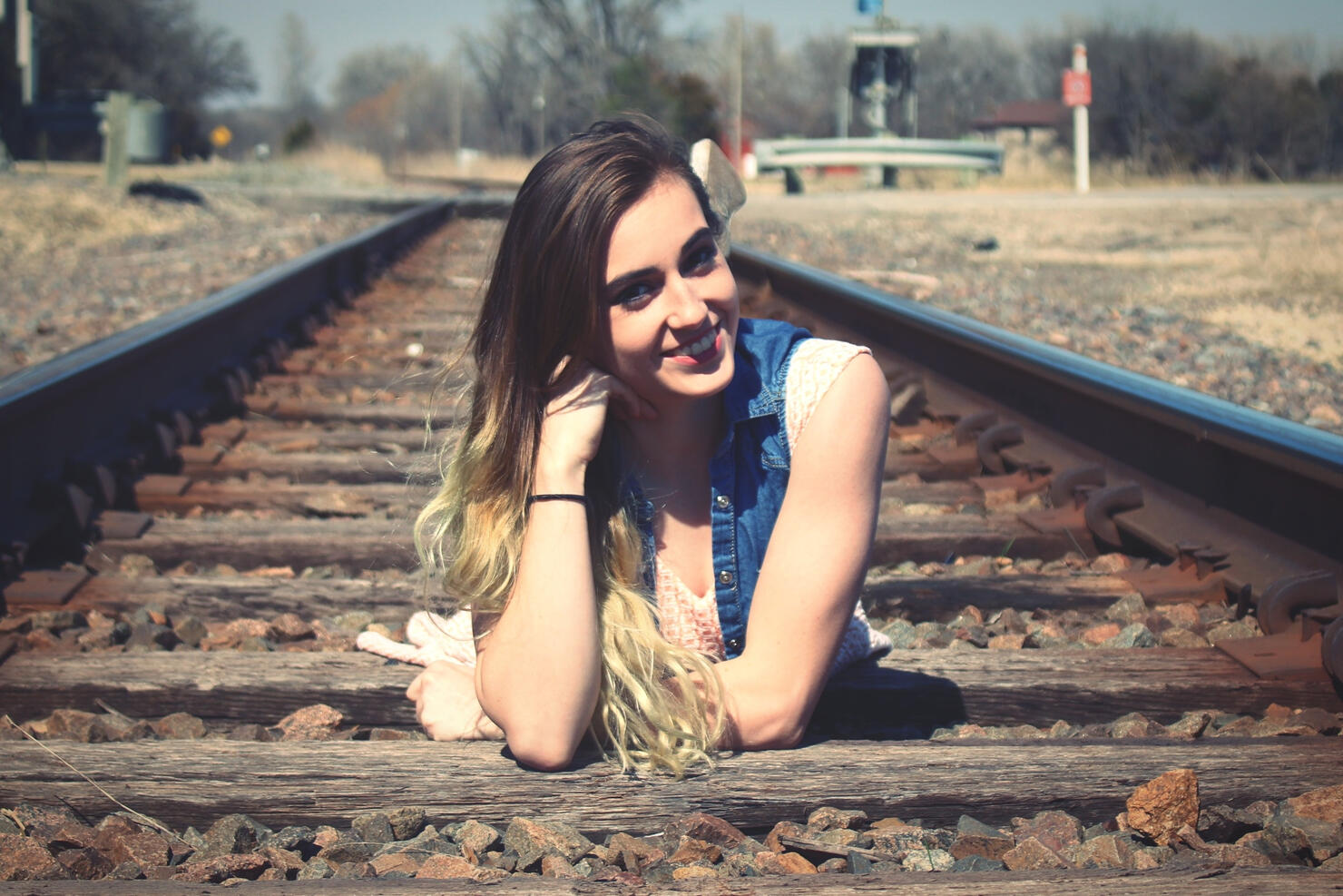 Portrait Of Smiling Young Woman Lying On Railroad Track