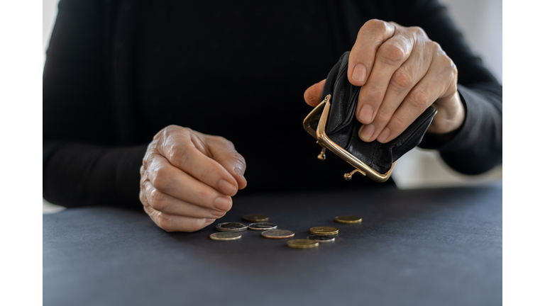 An elderly woman holds an open empty wallet in her hands, the concept of poverty, pension