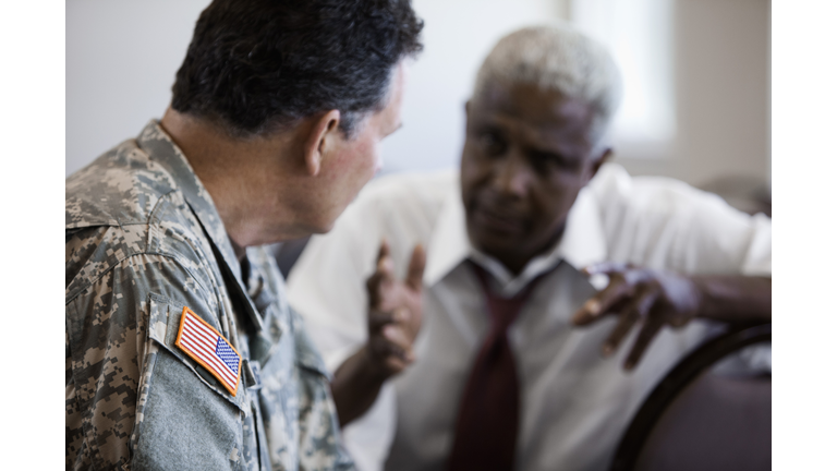 Soldier sitting in chair talking to businessman
