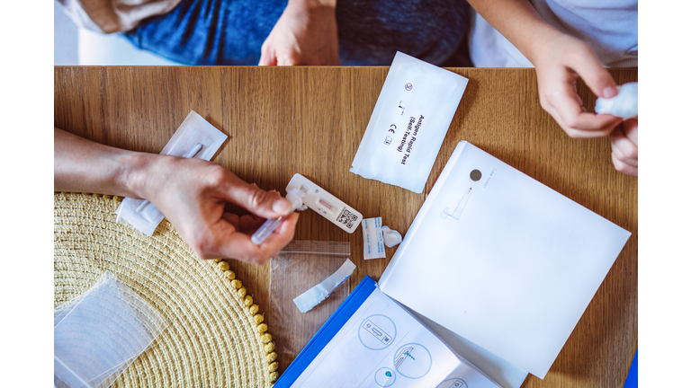 Directly above view of mom using Covid-19 rapid self-test kit for her kid at home