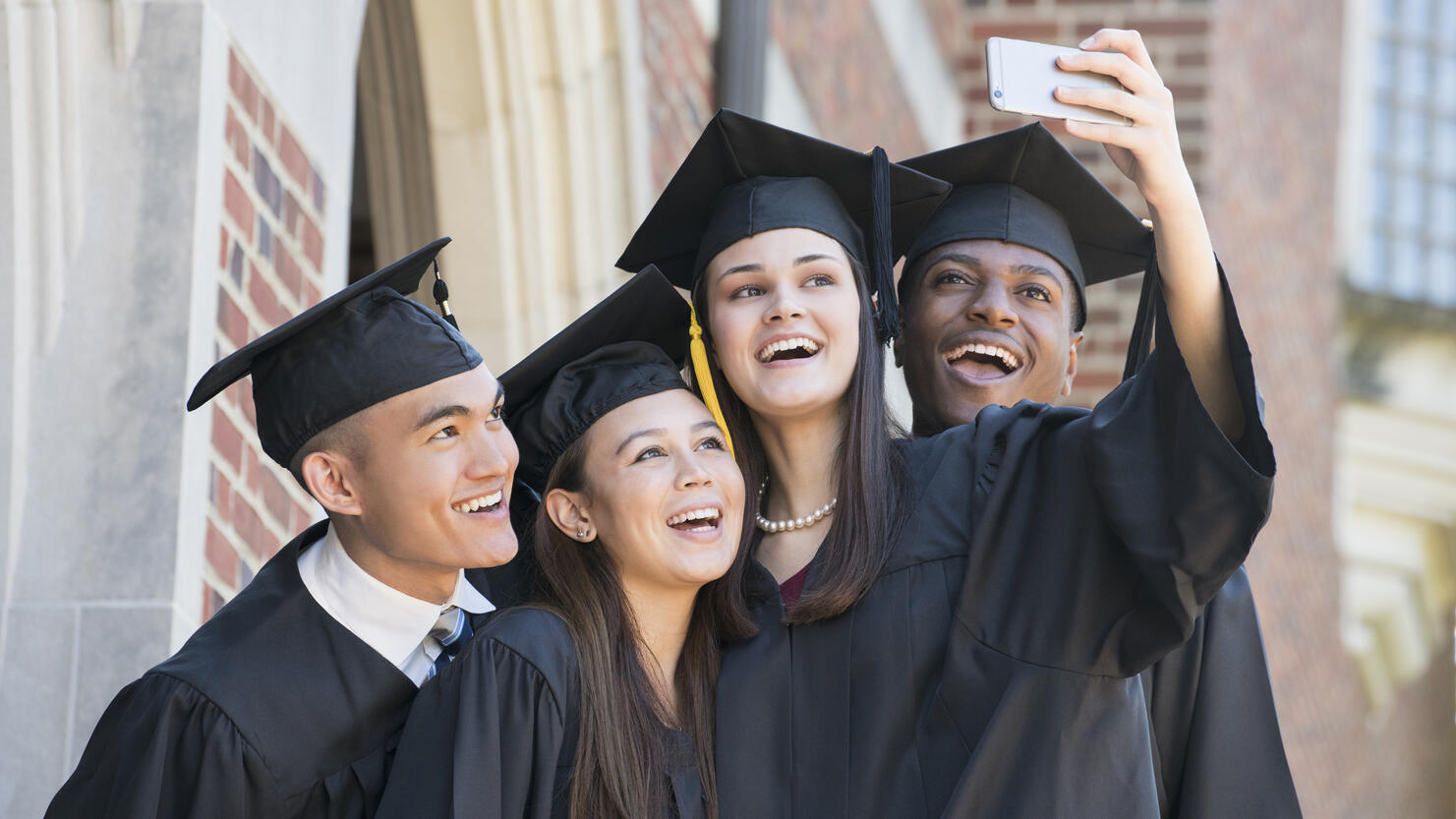 Students posing for cell phone selfie at graduation