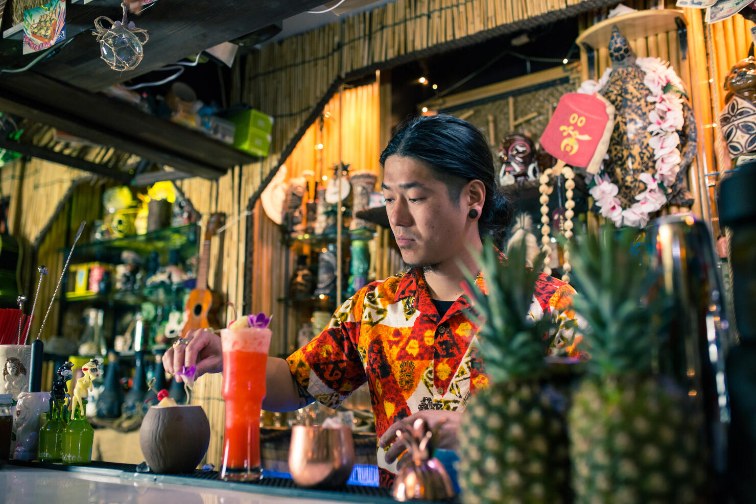 Bartender mixing cocktails and making drinks in a tropical themed restaurant or bar