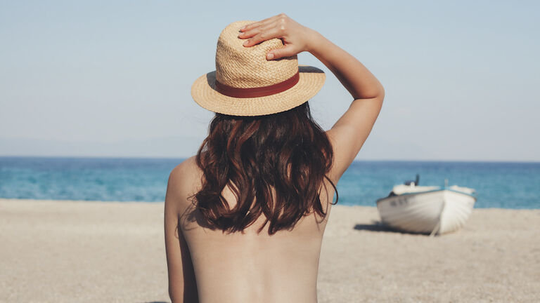 Greece, young woman on the beach looking at the sea