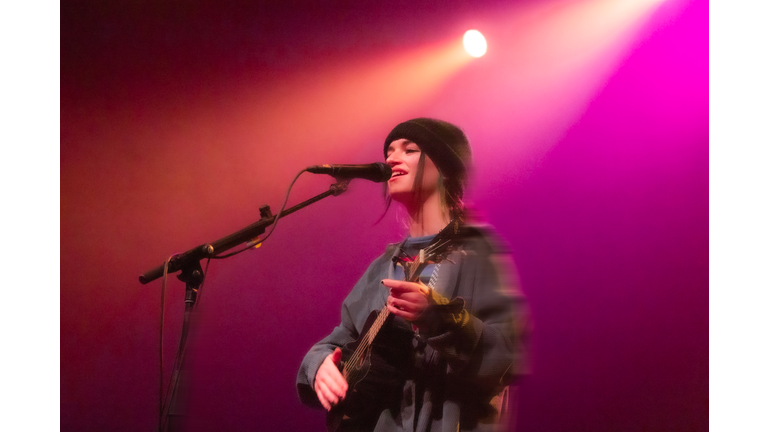 distorted photo of singer with guitar in pink and red light