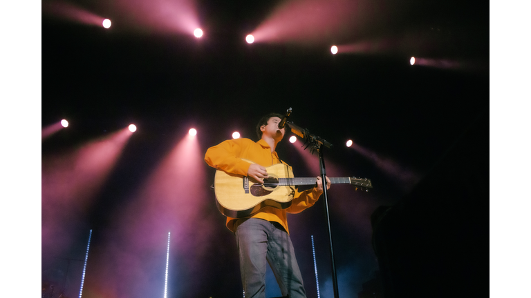 male singer with guitar, red and blue lighting overhead