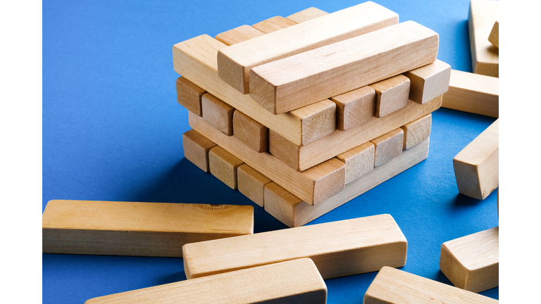 A Pile Of Scattered Wooden Blocks On A Blue Background. Construction game. Build an Unfinished and Destroyed tower.