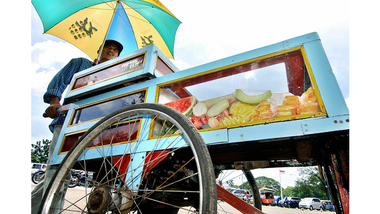 A fruit vendor pushes his cart as he sea