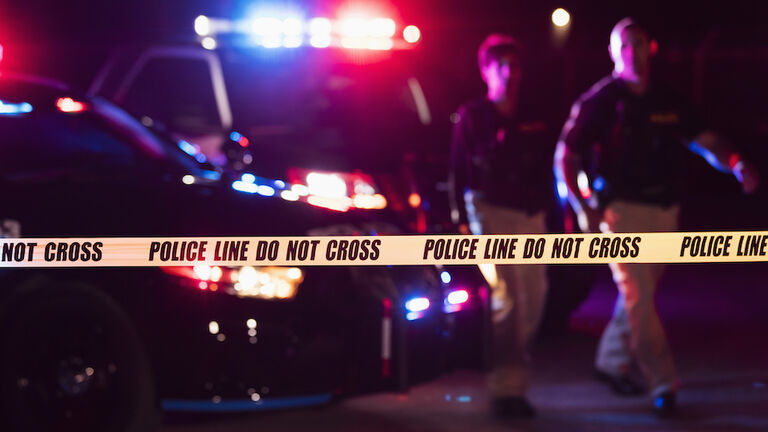 Two police officers behind crime scene tape