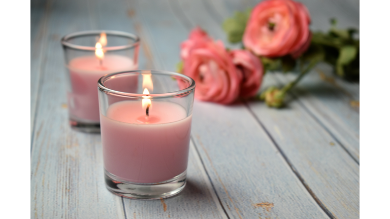 Scented pink candles with flowers in the background