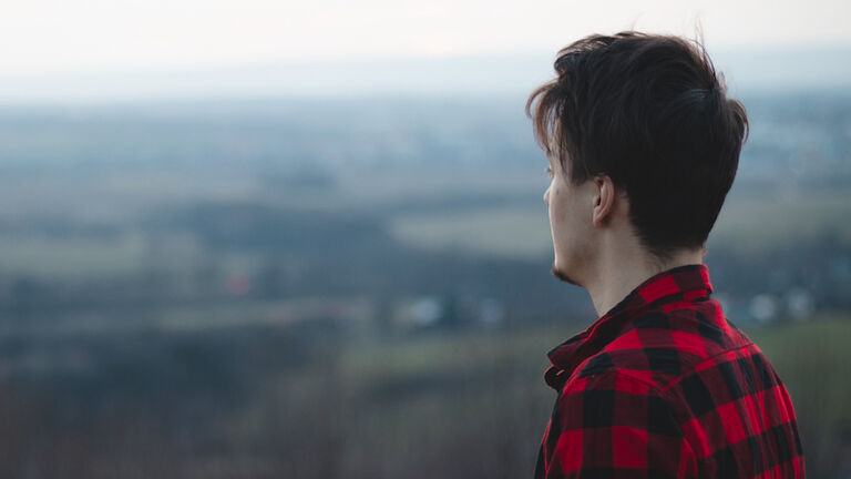 Candid Portrait Of A Man In His 20S Dressed In A Black And Red Checked Shirt Looking Into His Future
