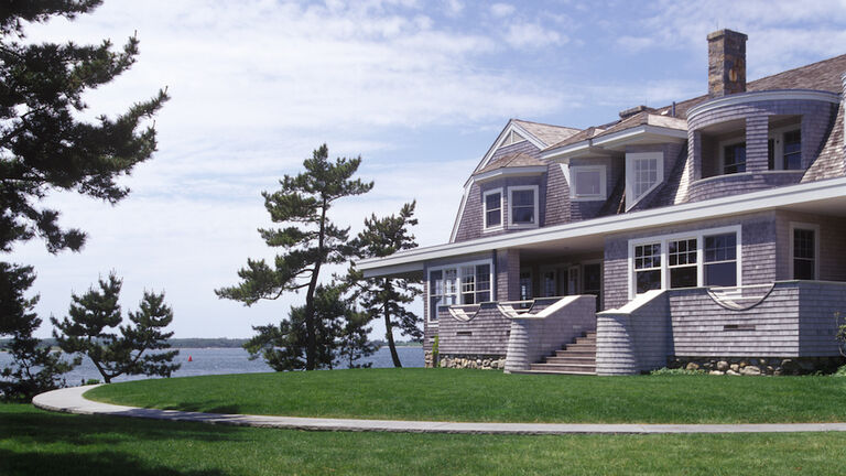 Grass yard and concrete walkway in front of two-story wood shingle home