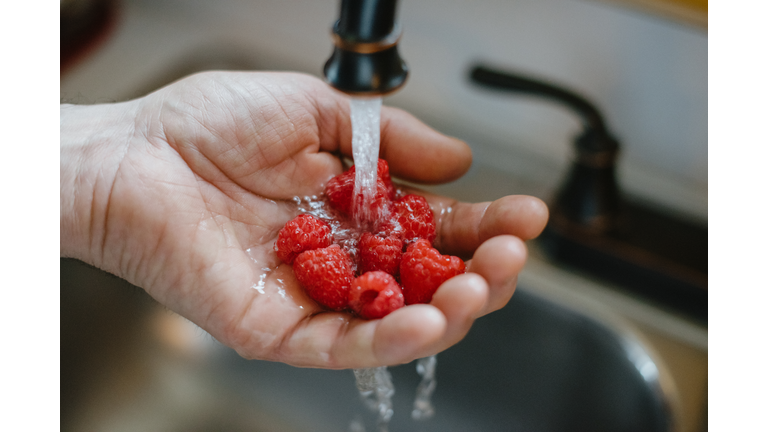 Male Hand Under Running Water to Wash Raspberries