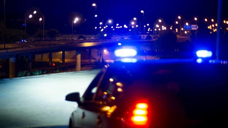 Police car with bright sirens and the city in the background