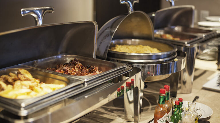 Prepared food in warming dishes on buffet
