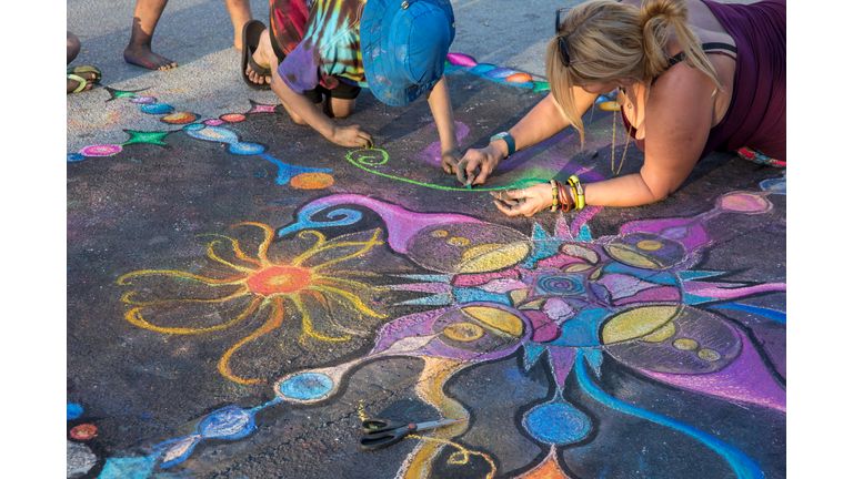 Children help artist with her street art work at Lake Worth Street Painting Festival