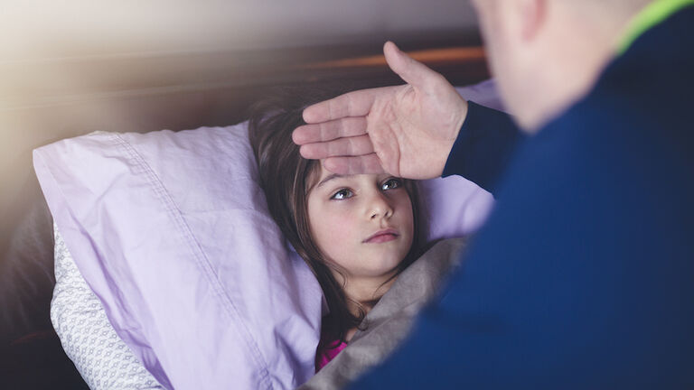 father checking daughter's forehead for fever