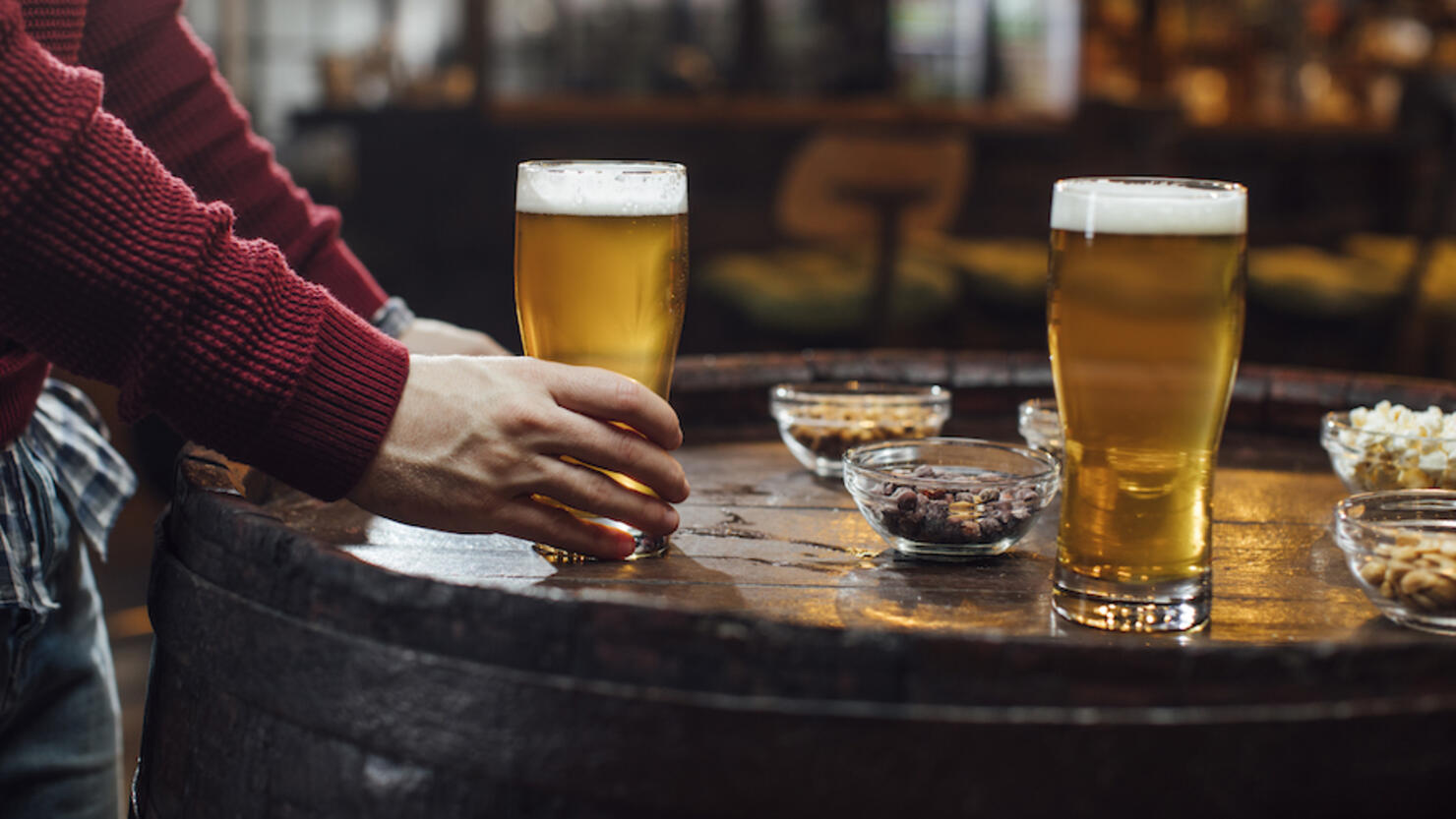 Anonymous Man Standing in a Pub Holding a Glass of Cold Beer