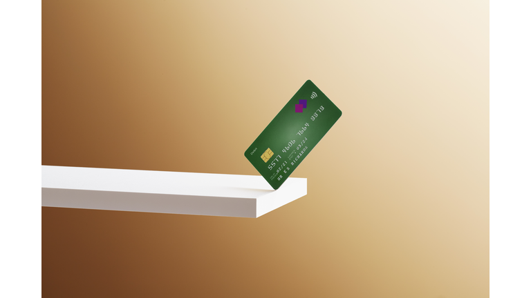 A debit card balanced on the edge of a shelf