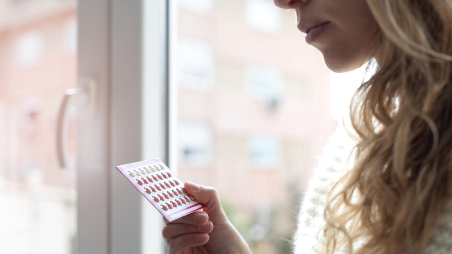 Young woman holding contraceptive pills