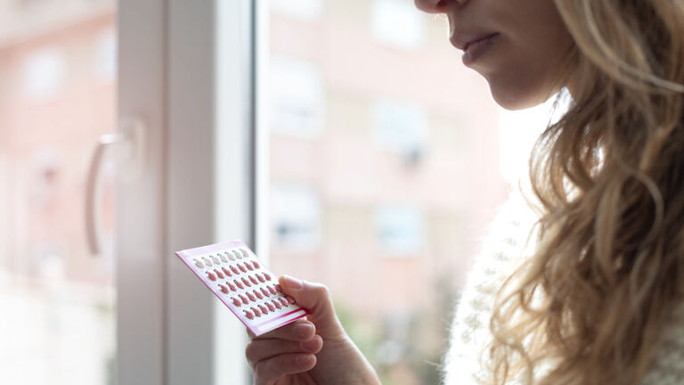 Young woman holding contraceptive pills