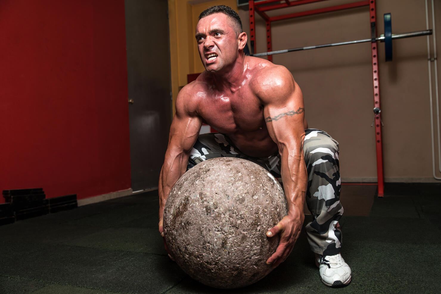 Bodybuilder in a contest trying to pick up a stone