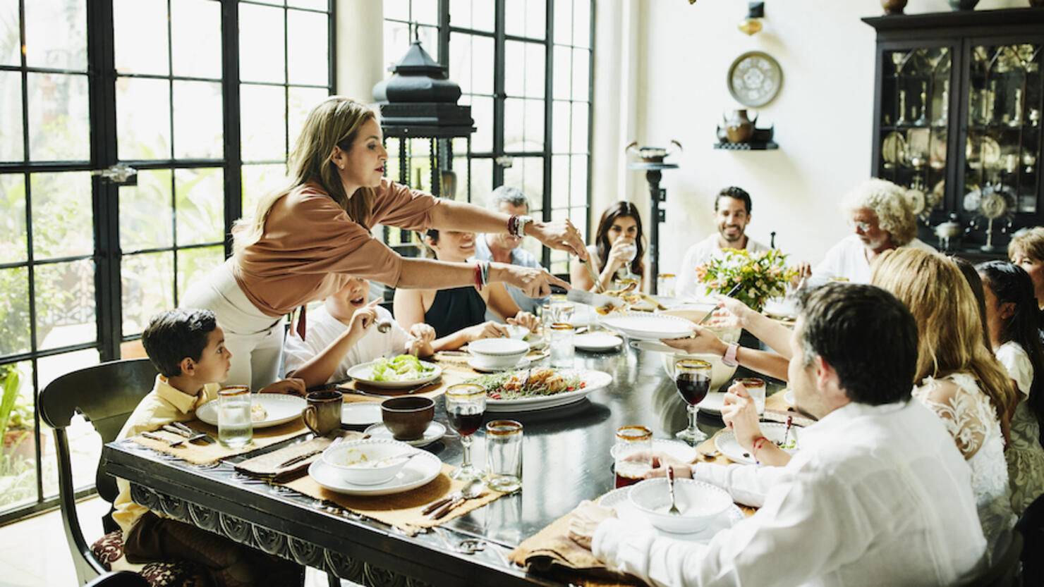 Woman serving family members at dining room table during celebration meal