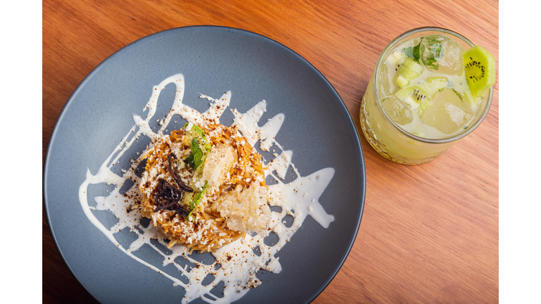 Fried noodle and alcoholic cocktail on wooden table.