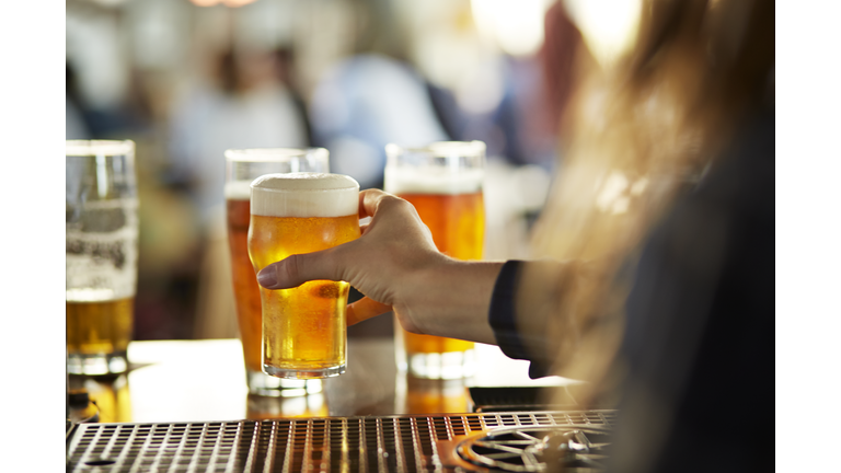 Close-up of bartender serving beers at bar