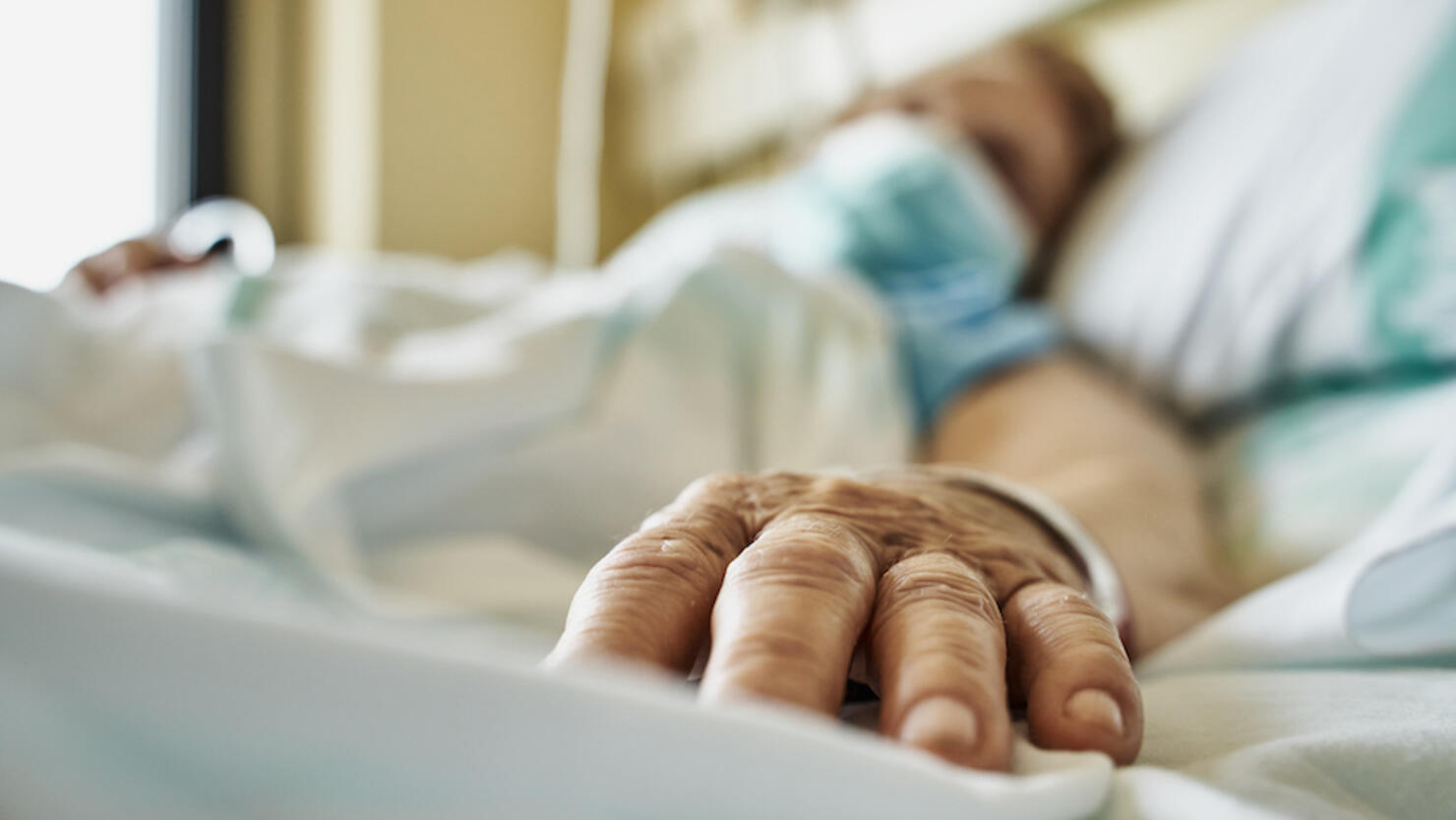 Senior woman wearing face mask lying on hospital bed