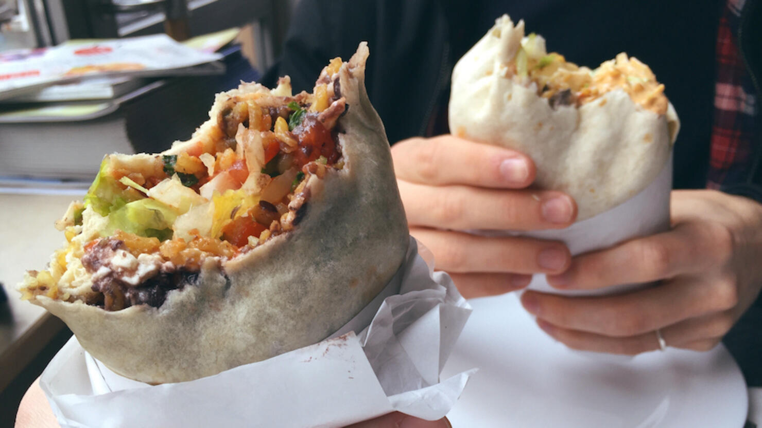 Cropped Hands Holding Burritos At Restaurant