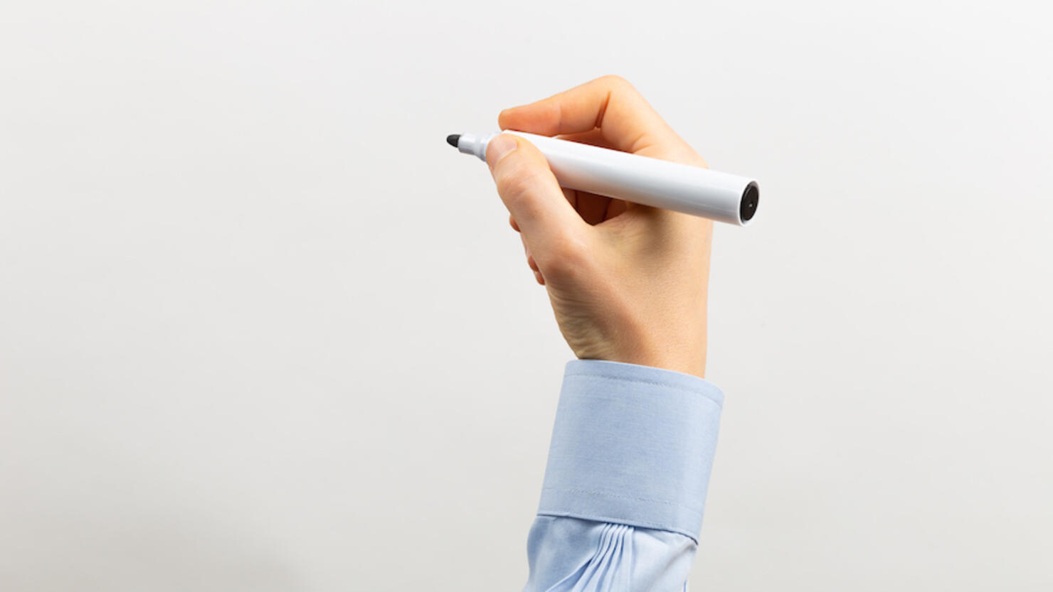 Rised arm writing with a black marker in a transparent white board