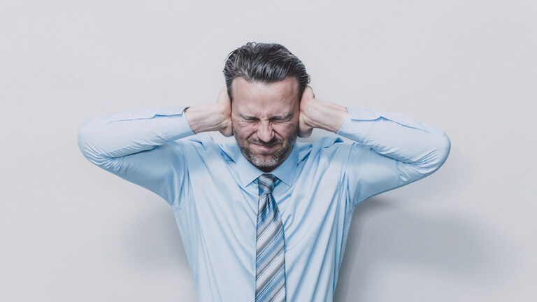 Business man covering his ears.
